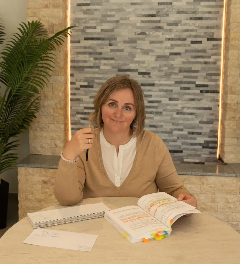 Eine Frau lernt am Schreibtisch und lächelt.
